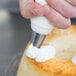 A person using an Ateco St. Honore piping tip on a pastry bag to frost a cake.