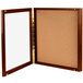 A wooden enclosed display case with a glass panel and cork board inside.