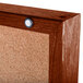 A cork bulletin board with a cherry finish and a hinge.