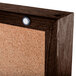 A white cork bulletin board with a hinged door with a walnut frame.