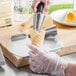 A person using a Waring waffle cone forming tool to make an ice cream cone.