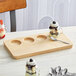 An Acopa natural wood flight tray with jars of dessert on it.