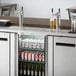 An Avantco stainless steel kegerator with two beer tap towers on a table.
