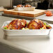 A Vollrath aluminum roasting pan filled with chicken and vegetables on a counter.