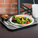 A Vollrath gray plastic fast food tray with a salad and muffin on it.