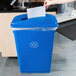 A hand puts paper into a blue Lavex recycling can with a slot.