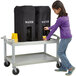 A girl pushing a Cambro Hydration Station cart with beverage dispensers.