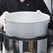 A person in a chef's uniform holding a white Town rice cooker pot.