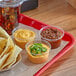 A clear plastic container of Carnival King chili sauce on a table with a variety of dips.