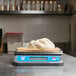 A dough ball in a plastic container on a blue digital scale.