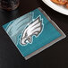 A Philadelphia Eagles beverage napkin with a logo of a bird on a table.