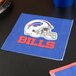 A blue and white Creative Converting Buffalo Bills luncheon napkin with a football helmet on it on a table.