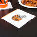A Cincinnati Bengals luncheon napkin with a football helmet on it next to a plate of chicken wings.