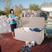 A woman standing on a deck next to a Lifetime outdoor storage box filled with cleaning supplies.
