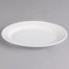 A white porcelain small oval pickle dish with a rim.