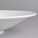 A close-up of a Villeroy & Boch white porcelain coupe deep plate with a rim.