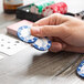 A hand holding a blue and white Bicycle poker chip.