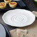A white Villeroy & Boch La Scala porcelain saucer with a circular design holding small pastries on a table.