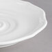 A close-up of a white Villeroy & Boch La Scala saucer with a wavy design.