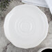 A white Villeroy & Boch porcelain saucer on a table next to a cup of coffee.