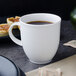 A Villeroy & Boch white porcelain mug filled with coffee on a table with pastries.