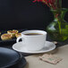 A Villeroy & Boch white porcelain cup of coffee sits on a table with a plate of pastries.