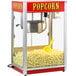 A Paragon red and white popcorn machine with popcorn in it and a yellow scoop.