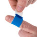 A person putting a San Jamar blue bandage on a finger.