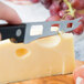 A person cutting cheese with a Franmara serrated cheese knife.