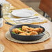 A Choice pre-seasoned cast iron skillet filled with fried chicken on a table.