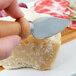 A person cutting hard cheese with a Franmara stainless steel cheese knife with a beechwood handle.