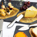 An American Metalcraft stainless steel hard cheese knife on a plate with cheese and grapes.