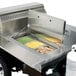 A Crown Verity portable outdoor grill with a stainless steel tray of food.