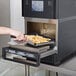 A person using a Merrychef eikon e2s countertop oven to cook french fries.