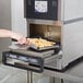 A person cutting french fries in a Merrychef eikon e2s countertop oven.