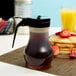A Tablecraft syrup dispenser filled with syrup on a table with pancakes.