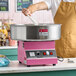 A pink Carnival King cotton candy machine with a 21-inch stainless steel bowl being operated on a countertop.