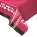 A red plastic Creative Converting table cover with white Arizona Cardinals text on a table.