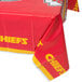 A red and yellow Creative Converting Kansas City Chiefs plastic table cover on a table.