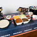 A table with a Chicago Bears plastic table cover and bowls of food on it.