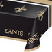 A black and gold Creative Converting New Orleans Saints plastic table cover on a table with a black and gold logo.