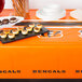 A Cincinnati Bengals table cover on a table with plates of food and snacks.