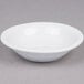 A Tuxton bright white china fruit bowl on a gray surface.