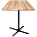 A Holland Bar Stool natural wood table top with a black cross base.