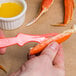 A person using a pink Choice Shuckaneer seafood sheller to peel a crab leg.