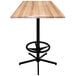 A Holland Bar Stool natural wood square bar table with a black metal base.