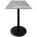 A Holland Bar Stool outdoor bar height table with a black base and a greystone top.