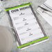 A Menu Solutions Alumitique menu board with green bands on a table with silverware and a napkin.