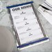 An Alumitique menu board with navy bands on a table with a fork and knife.