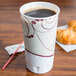 A Solo Symphony foam cup filled with a beverage on a table with croissants.